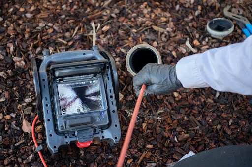 Sewer line inspection camera being inserted into exterior cleanout pipe
